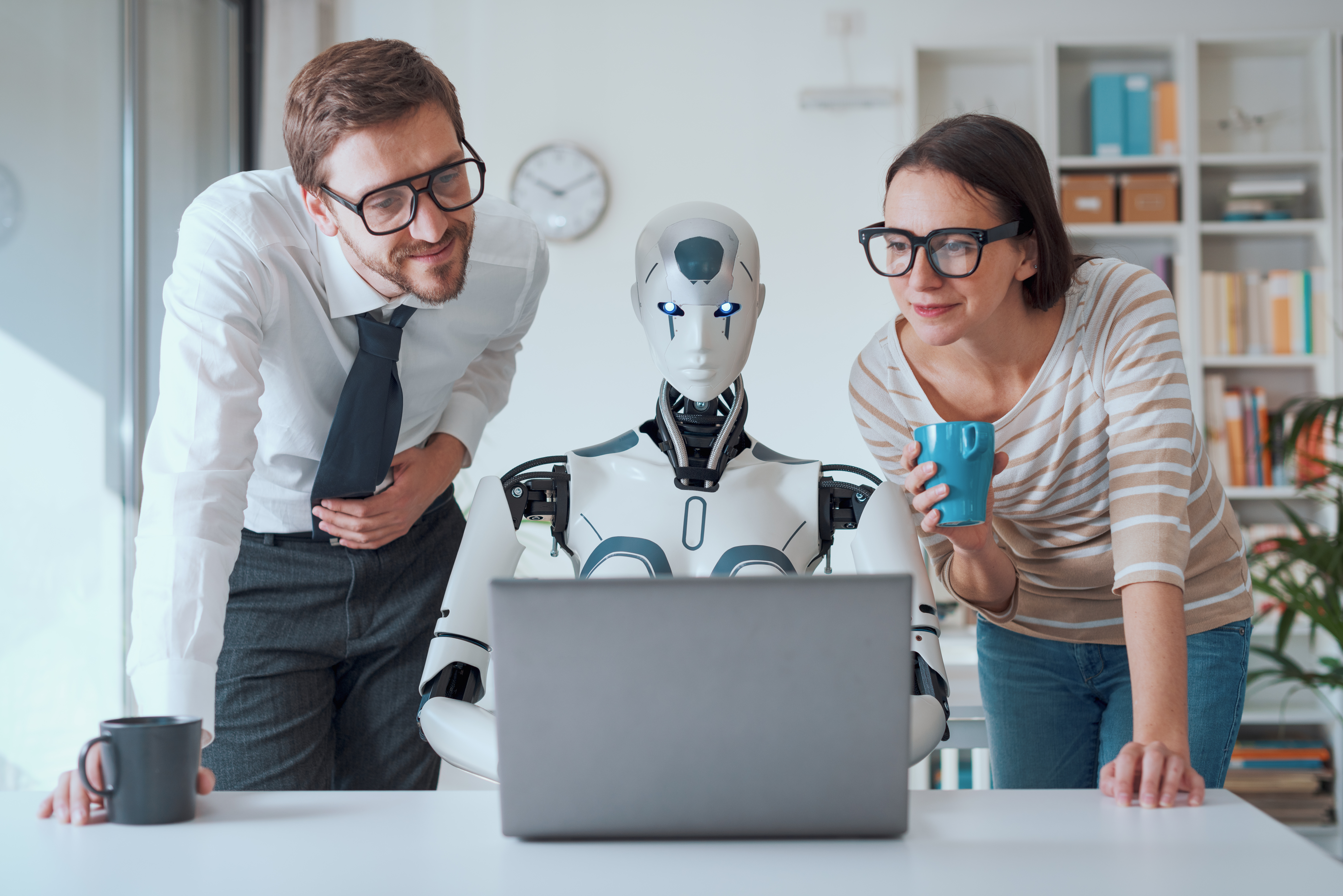 Man and Woman sat looking at computer screen with a robot