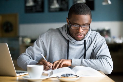 young student making notes with pen and paper 