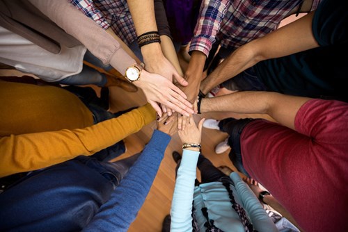 People placing their hands together in a circle to symbolize collaboration