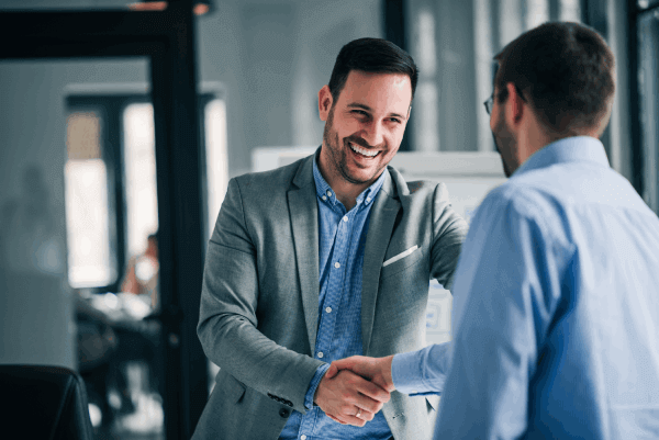 Two professionally dressed men shaking hands, suggesting success