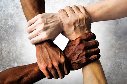 hands of all people from all different ethnicities interlinked together 