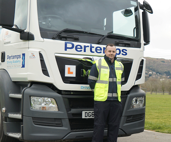 man stood in front of pertemps lorry with L plate on it. 